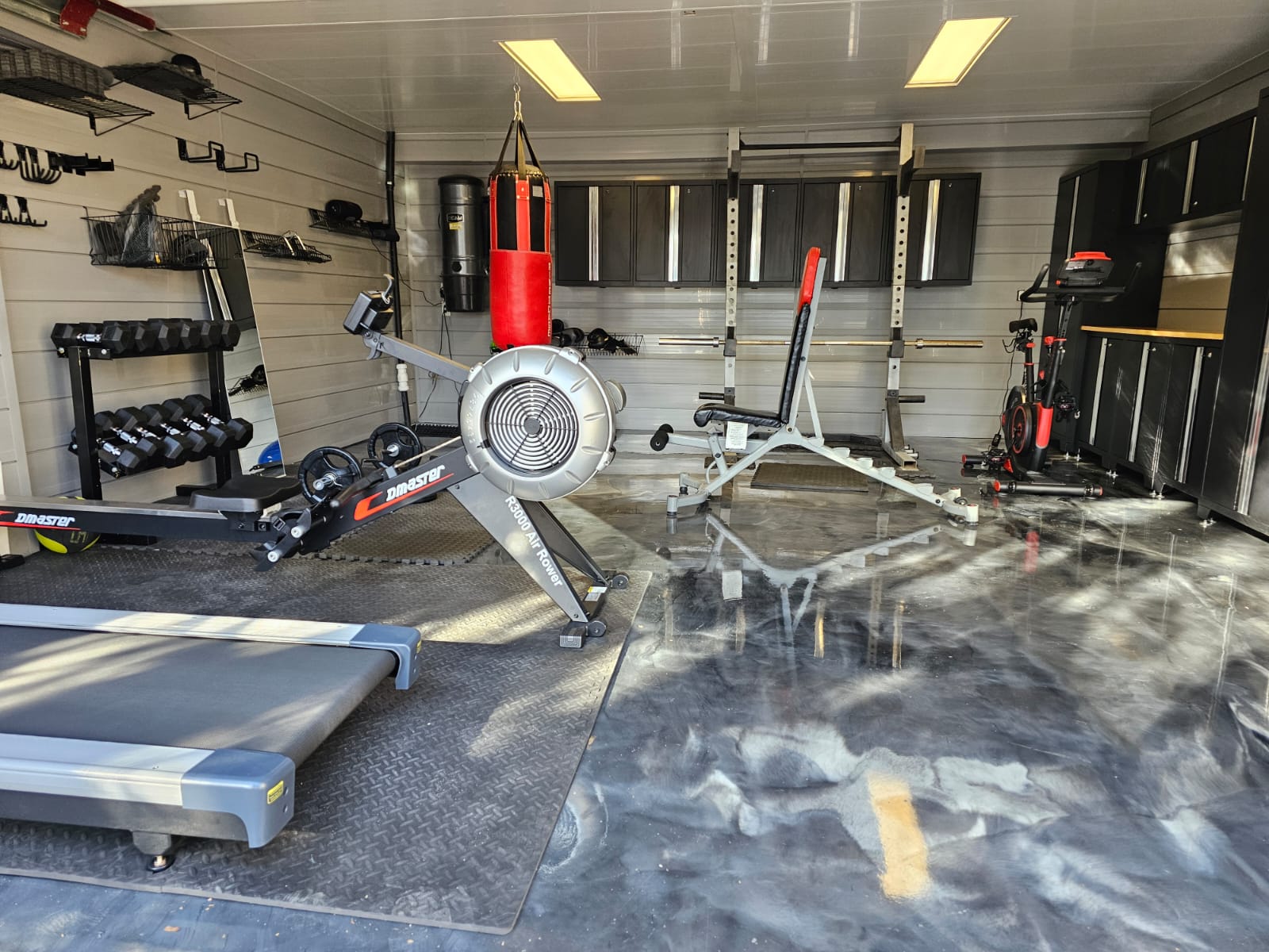 A converted garage home gym with rubber flooring, LED lighting, and organised equipment storage